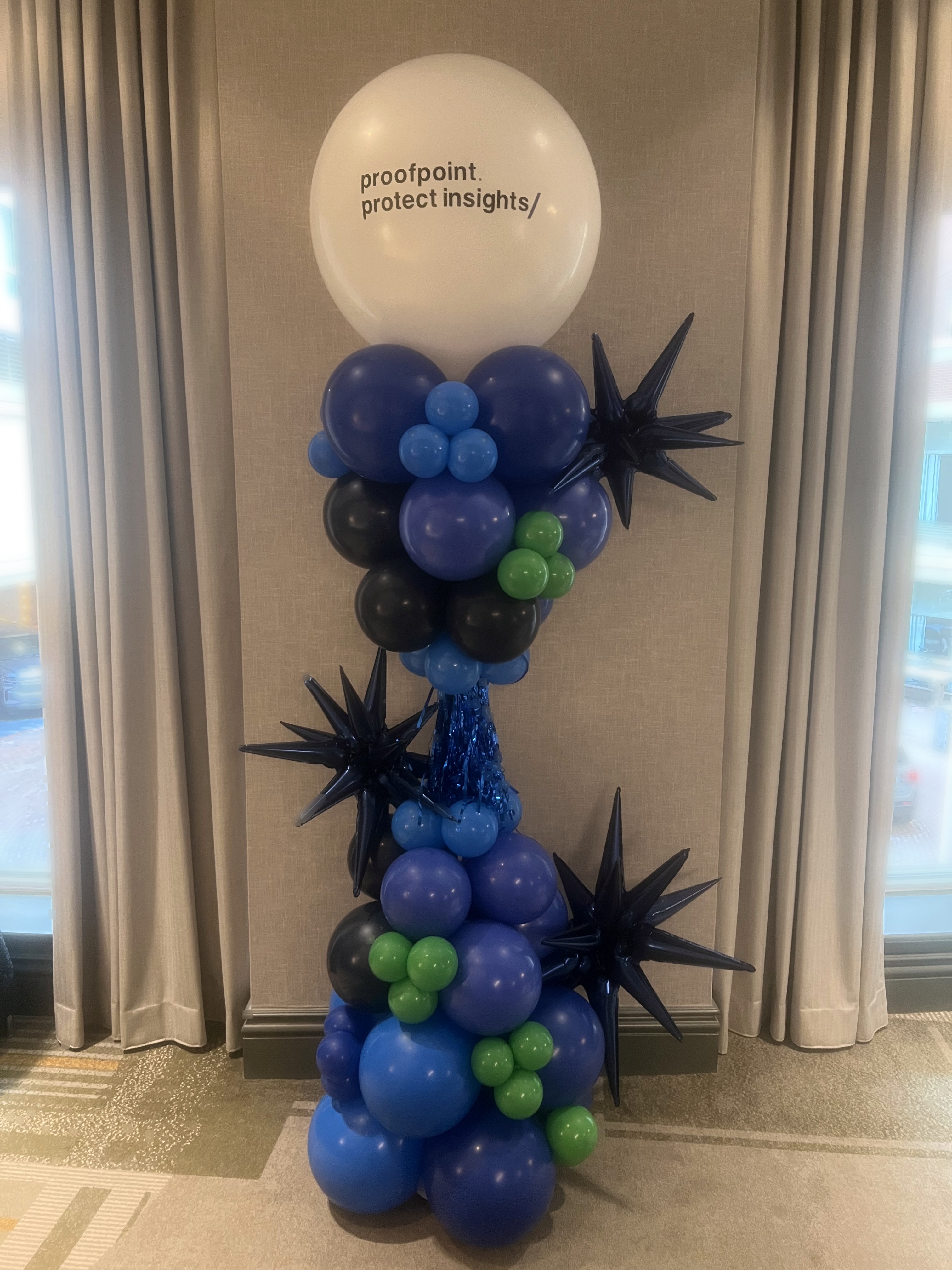 Blue and emerald green branded balloon topiary with corporate Proofpoint signage