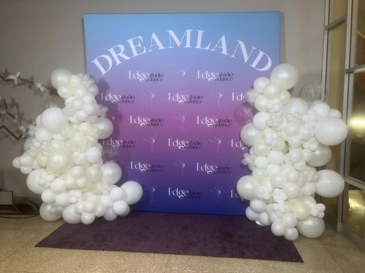 White organic balloon garlands flanking a vibrant purple Dreamland conference backdrop